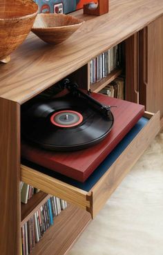 a record player sitting on top of a wooden shelf next to a bowl and bookshelf