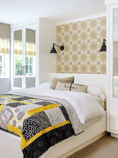 a white bed with yellow and black quilt on it