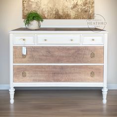 a white dresser with two drawers and a potted plant on top