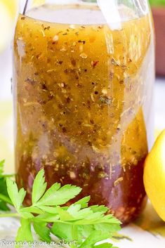 a jar filled with liquid sitting next to an apple and some green leafy leaves