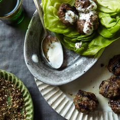 some meatballs and lettuce are on a plate with a spoon next to it