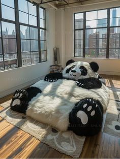 a giant panda bear bed in the middle of a room with large windows and wooden floors