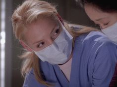 two women in scrubs and masks are looking at something