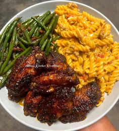 a plate with pasta, green beans and chicken wings