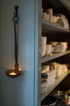 a shelf filled with plates and bowls next to a wall mounted tea light candle holder