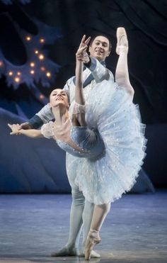 two ballerinas are performing on stage with one holding the other's leg