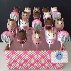 there are many cupcakes shaped like horses on the sticks in this pink box