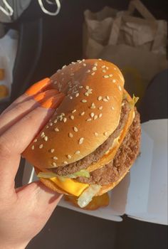 a hand holding a hamburger with cheese and lettuce