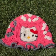 a crocheted hello kitty hat laying on the grass