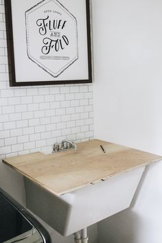 a bathroom with a sink, mirror and framed sign on the white wall above it