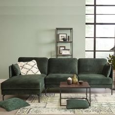 a living room with green couches and rugs on the floor in front of a large window