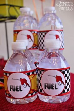 four bottles of fuel on a table with red and black checkerboard paper around them