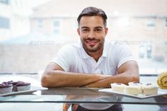 a man sitting at a table in front of some desserts and pastries - stock photo - images