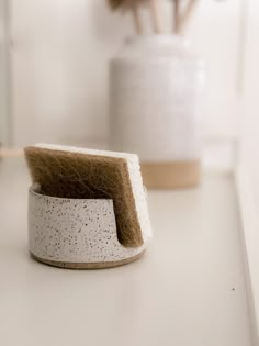 a close up of a brush on top of a white counter with flowers in the background