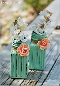 two vases with flowers in them sitting on a wooden table next to each other