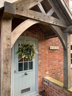 a white door with a wreath hanging on it's front porch next to a brick building