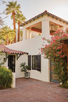 a white house with black shutters and red brick walkway leading to the front door