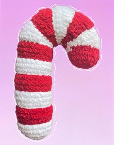 a crocheted candy cane on a pink background