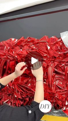 a woman is painting red foil on a wall