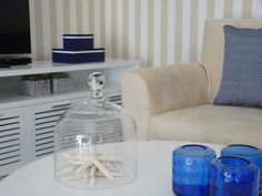 a living room with white furniture and blue glass jars