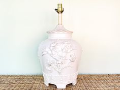 a white vase sitting on top of a wicker table next to a lamp shade