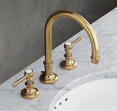 two golden faucets on a marble counter top