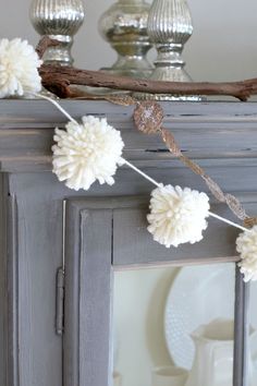 some white pom poms are hanging on the mantle