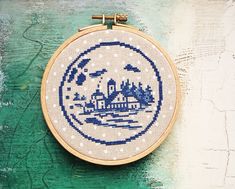 a blue and white cross - stitch pattern on a wooden hoop hanging from a wall