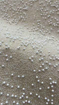 white balls are on the sand and water droplets have been placed on them to create an interesting pattern