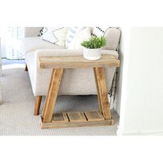 a small wooden table sitting in front of a couch with a potted plant on it