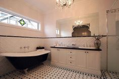 a black and white bath tub sitting next to a sink in a bathroom under a window