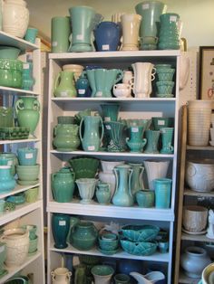 shelves filled with lots of green and white pottery