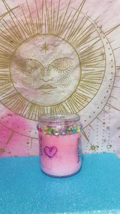 a pink candle sitting on top of a blue table next to a sun and moon