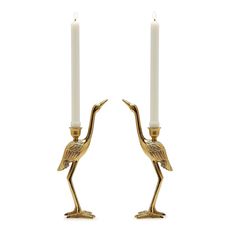 two gold flamingos are standing next to each other with candles in their beaks