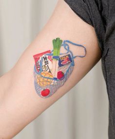 a person with a tattoo on their arm that has food in a basket and vegetables