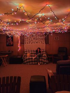 a woman sitting on top of a bed under a ceiling covered in lights