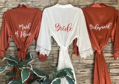 three bride robes hanging up against a brick wall