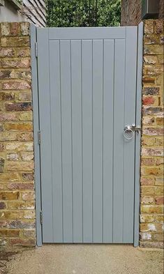 an open grey door in front of a brick wall