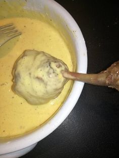 a bowl filled with yellow liquid and a wooden spoon in the bowl next to it