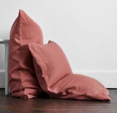 two pillows sitting on the floor next to a white wall and wooden floor in front of them