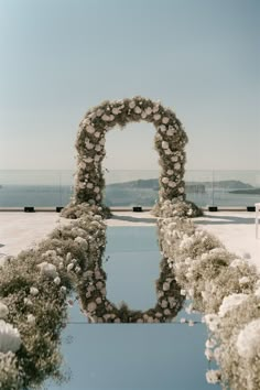 an arch made out of flowers is shown in the middle of a pool with water