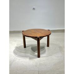 a round wooden table sitting on top of a white tile floor next to a wall