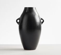 a black vase sitting on top of a white table