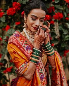 a woman in an orange sari holding her hands to her face while wearing jewelry