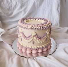 a three tiered cake sitting on top of a white tablecloth covered bedding