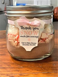 a jar filled with lots of candy sitting on top of a wooden table next to a sign that says thank you snow