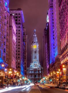 a city street at night with tall buildings and colorful lights on the building's sides