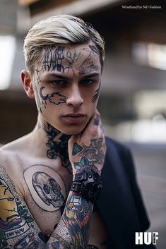 a man with lots of tattoos on his face and chest is looking at the camera