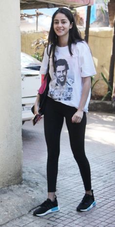 a young woman is standing on the sidewalk