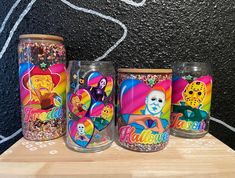 three decorated glasses sitting on top of a wooden table next to a chalkboard wall